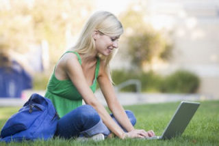 Young woman using laptop on grass